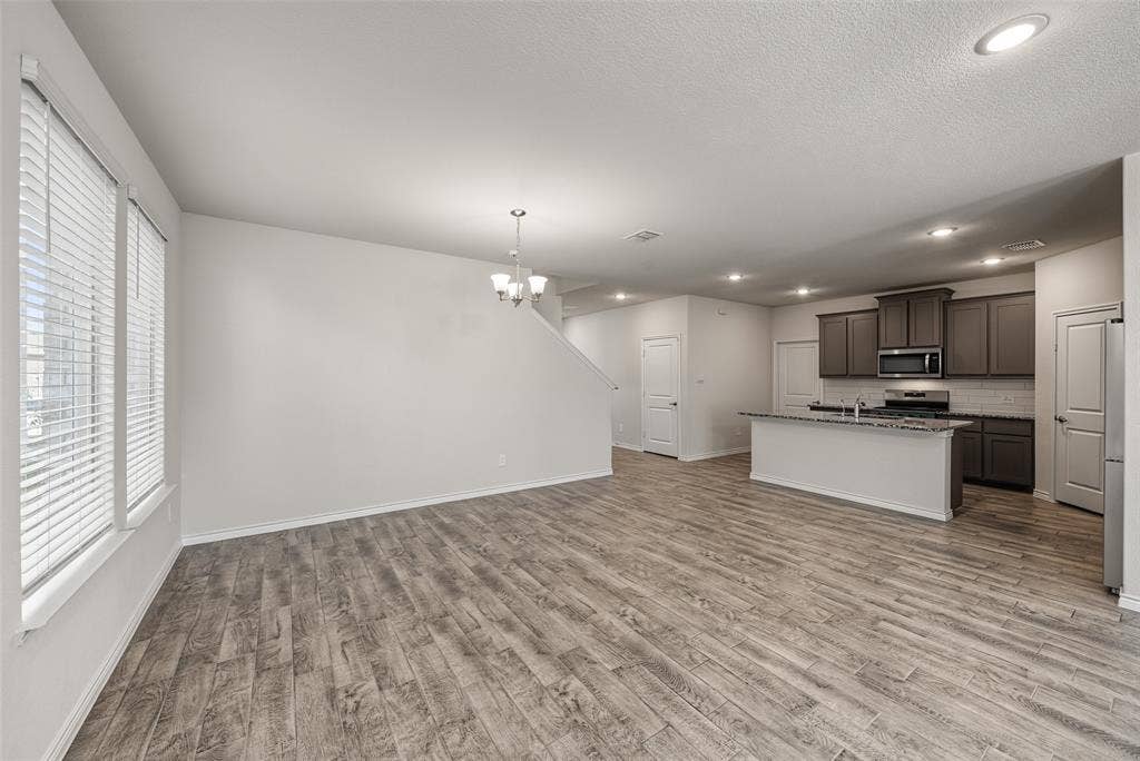 Open-concept living area featuring porcelain tile flooring, recessed lighting, and a modern kitchen with gray cabinetry, stainless steel appliances, and a central island with a breakfast bar