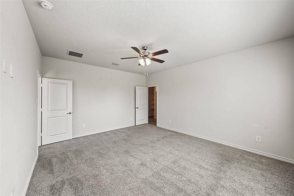 Neutral toned carpeting, contemporary ceiling fan with lighting, and multiple panel doors