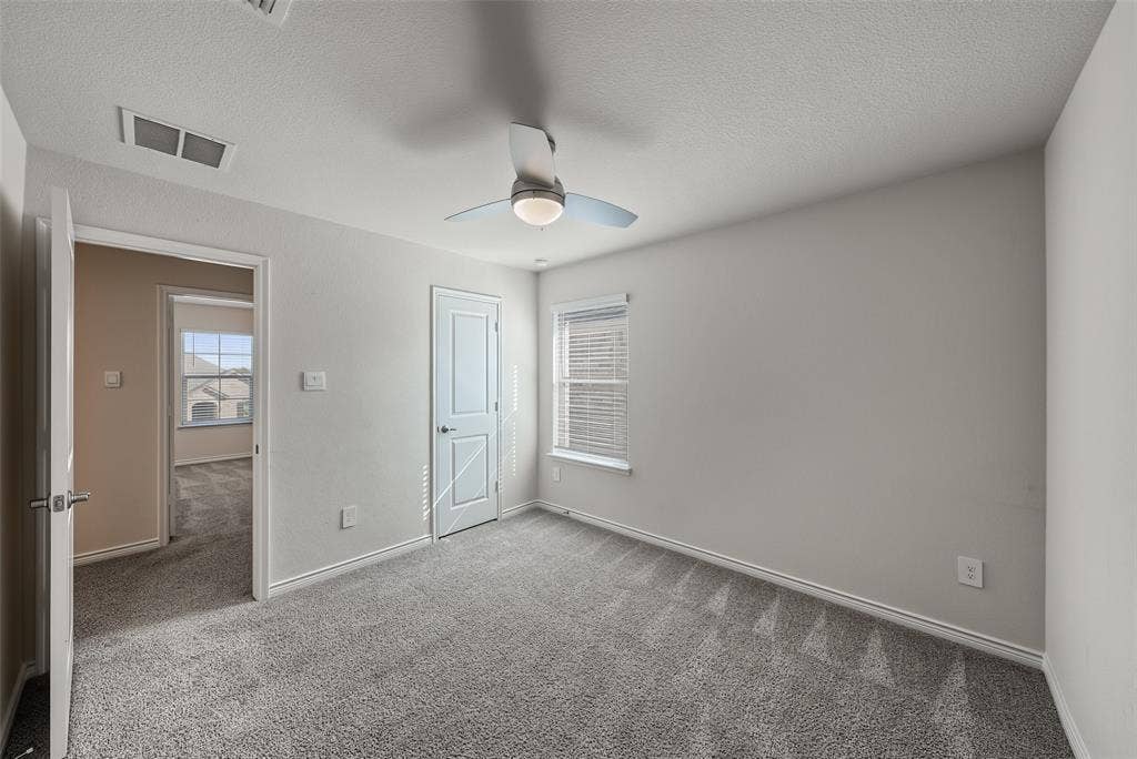 Plush gray carpeting, white trim work, ceiling fan with integrated lighting, and window with blinds