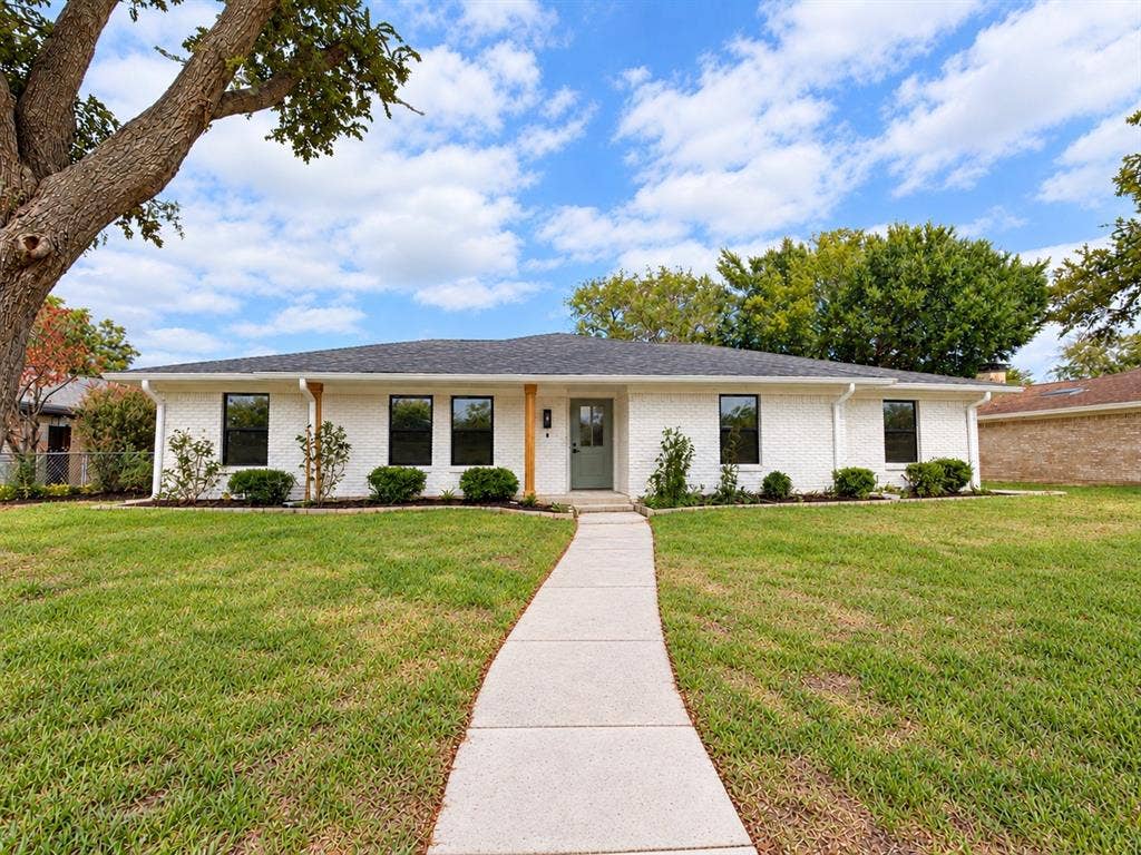 1521 Glenwick Drive, Plano, TX 75075 Single-story residence featuring a painted brick exterior, dark asphalt shingle roof, concrete walkway, and wood-wrapped front porch pillars