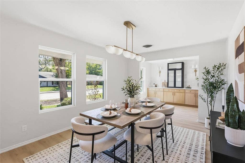 1521 Glenwick Drive, Plano, TX 75075 Dining area featuring wood-finish flooring, dual-pane windows, a linear multi-light pendant fixture, and a built-in cabinetry unit with a glass-front display cabinet
