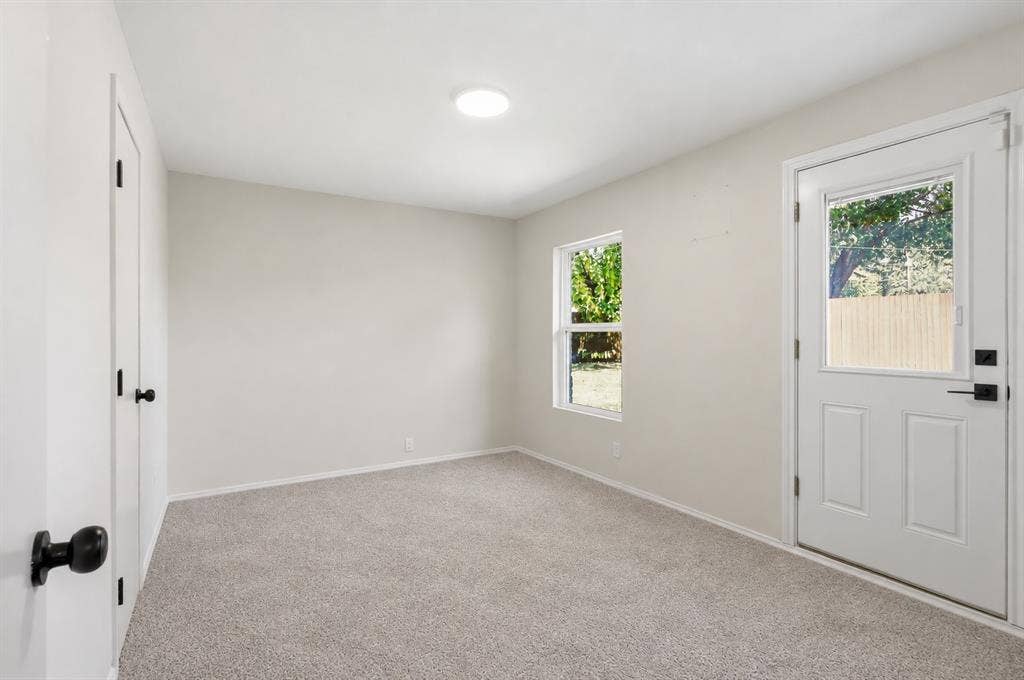 1521 Glenwick Drive, Plano, TX 75075 Neutral-toned interior space featuring carpeting, a white entry door with an integrated glass panel, a single window, and matte black door hardware