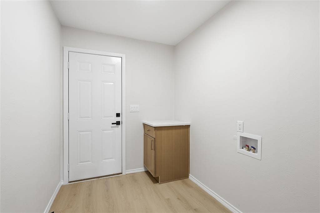 1521 Glenwick Drive, Plano, TX 75075 Utility room featuring wood-finish flooring, a built-in cabinet with a solid surface countertop, and dedicated washer and dryer hookups
