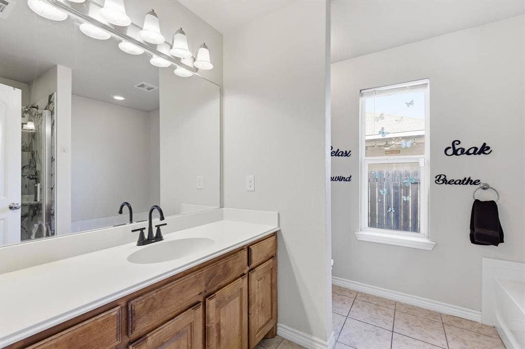 Dual-sink vanity with wood-finish cabinetry, light-toned countertop, and matte black fixtures