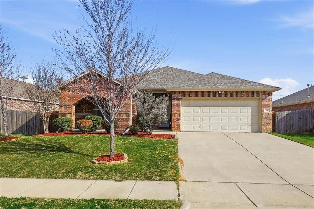 Brick exterior, arched entryway, two-car garage, concrete driveway, and front landscaping