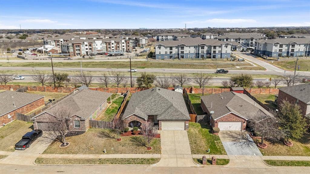 Brick exterior with an attached garage, paved driveway, and a fenced backyard
