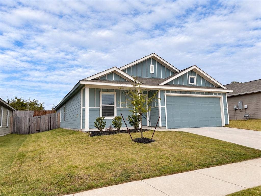 Attractive single-story home featuring blue siding with crisp white trim, an attached two-car garage, covered front entry, and landscaped front yard.