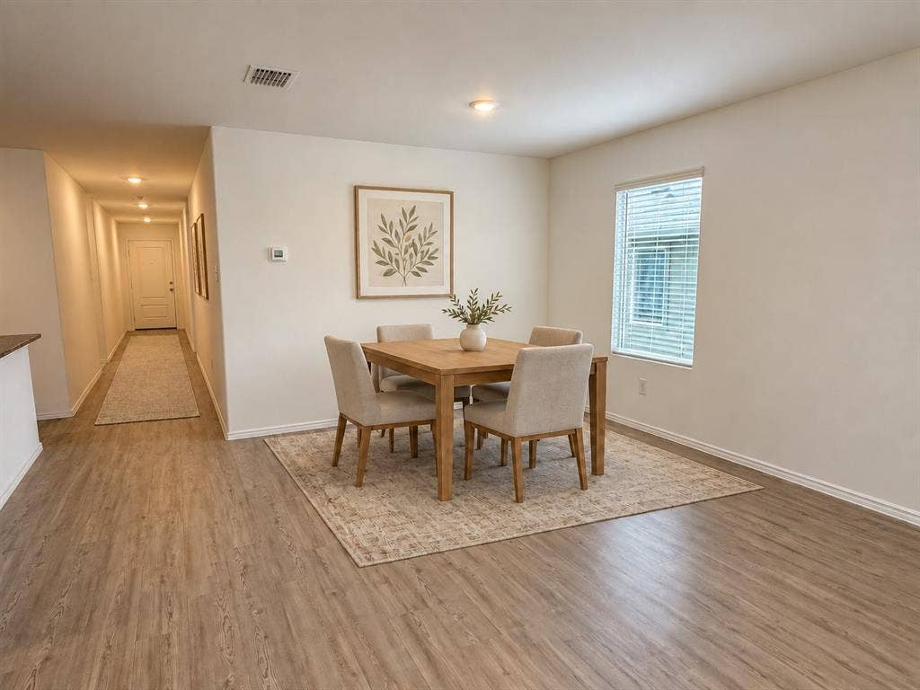 *Virtually Staged* Open dining area with luxury vinyl plank flooring, recessed lighting, and a large window providing natural light, with easy flow to the kitchen and living space.