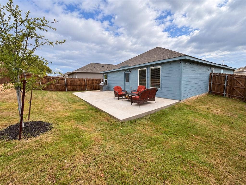 Spacious fenced backyard with an extended concrete patio offering plenty of room for outdoor seating, grilling, and entertaining.