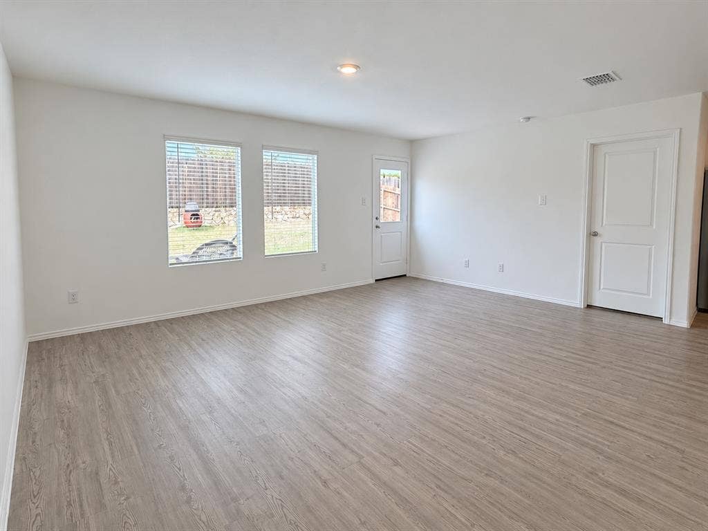 Spacious living area featuring luxury vinyl plank flooring, recessed lighting, abundant natural light, and direct access to the backyard.