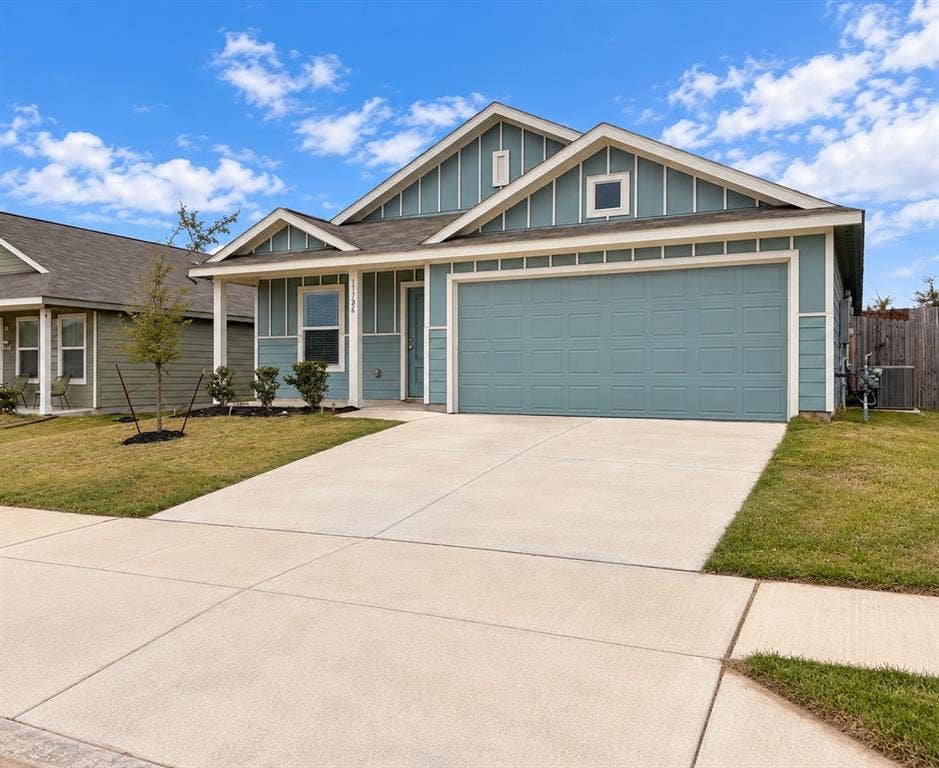 Attractive single-story home featuring blue siding with crisp white trim, an attached two-car garage, covered front entry, and landscaped front yard.