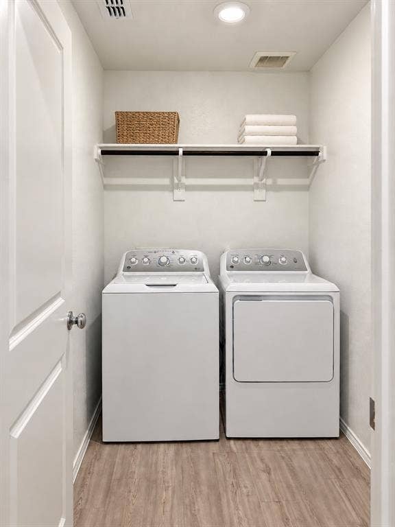 Dedicated laundry area with washer and dryer included, overhead storage shelving, recessed lighting, and luxury vinyl plank flooring.