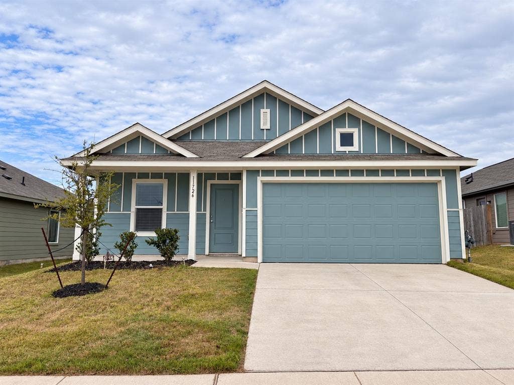 Attractive single-story home featuring blue siding with crisp white trim, an attached two-car garage, covered front entry, and landscaped front yard.