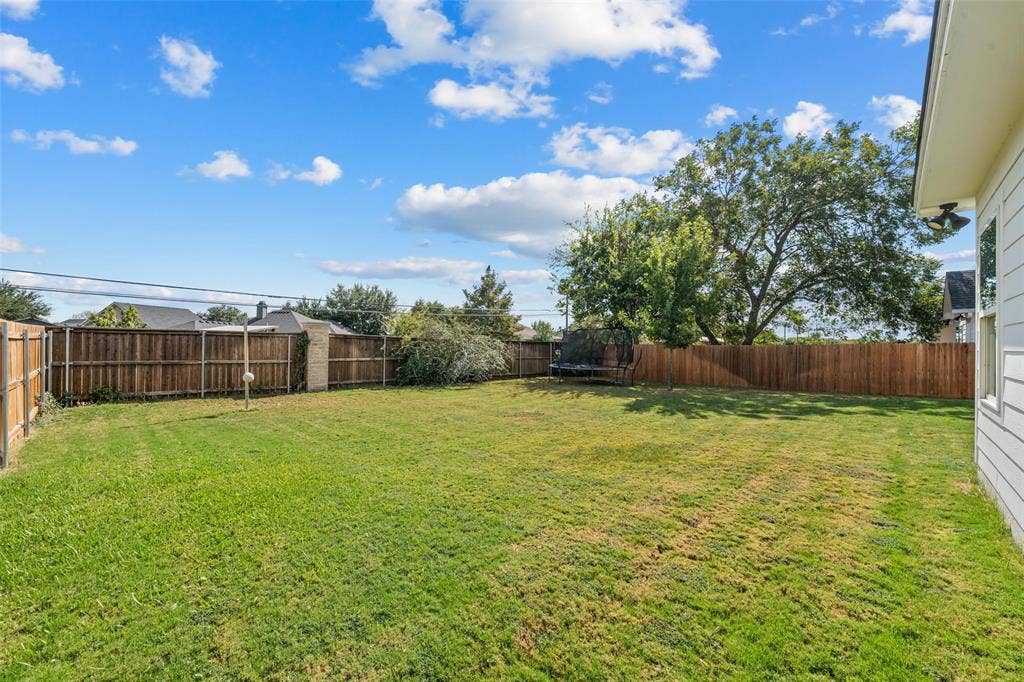 Expansive grassy yard with wood fencing and mature trees