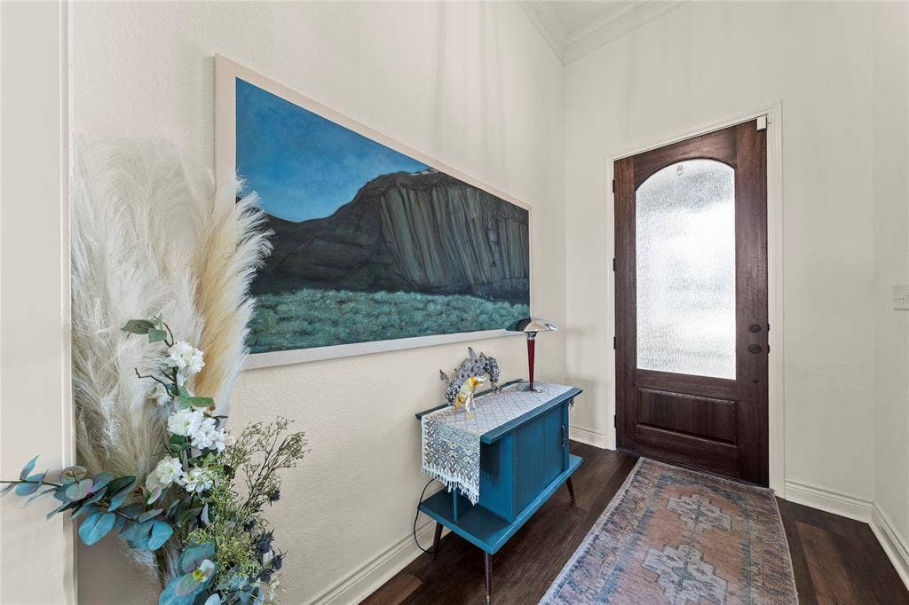Arched wood door with frosted glass panel, crown molding, and wood-finish flooring