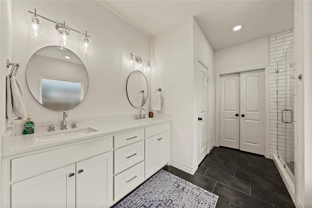 Dual vanity with white cabinetry and integrated sinks, complemented by circular mirrors