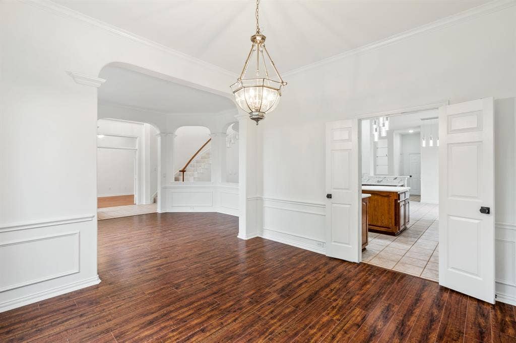 3307 Meadow Wood Drive, Richardson, TX 75082 Hardwood-style flooring, wainscoting, arched entryway, and a hanging chandelier