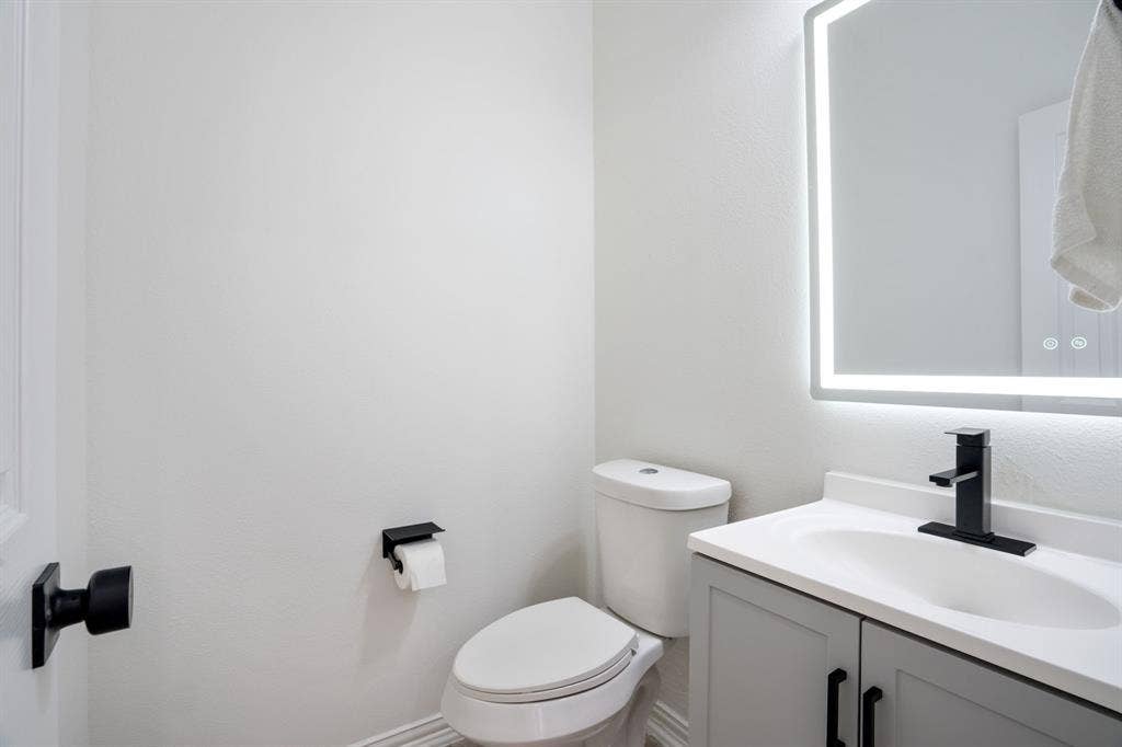 3307 Meadow Wood Drive, Richardson, TX 75082 Contemporary bathroom vanity with a white integrated sink, matte black faucet, and a backlit mirror