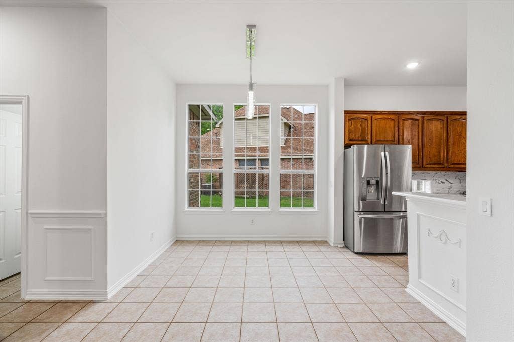 3307 Meadow Wood Drive, Richardson, TX 75082 Tile flooring, three large windows, recessed lighting, wood cabinetry, and a stainless steel refrigerator
