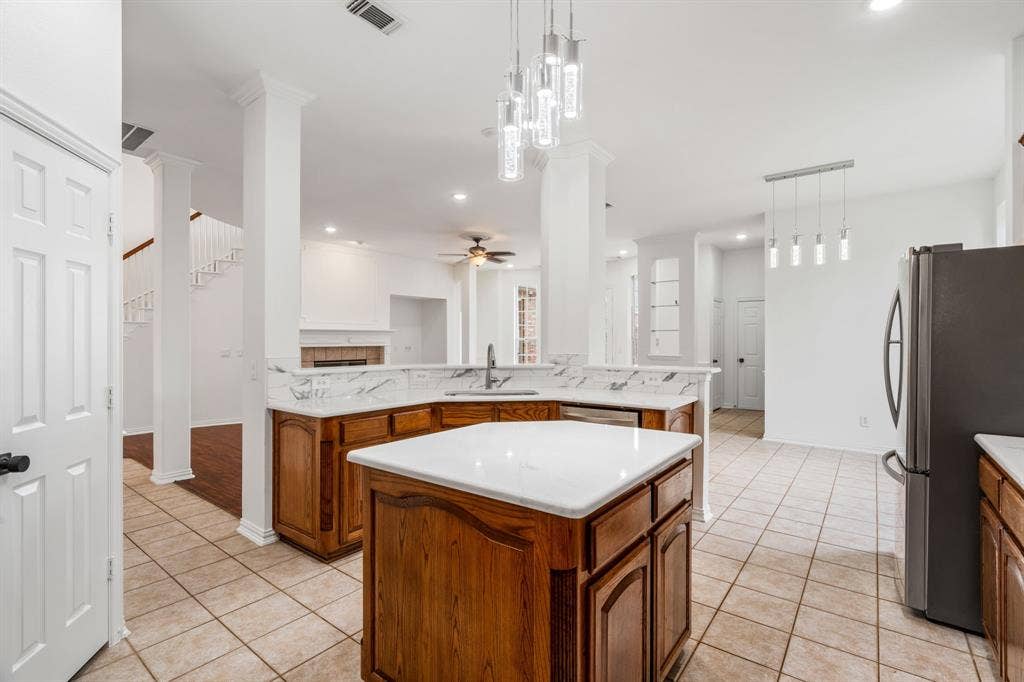 3307 Meadow Wood Drive, Richardson, TX 75082 Kitchen featuring a center island, wood cabinetry, stone countertops, and tile flooring
