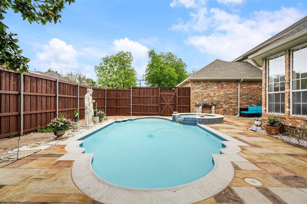 3307 Meadow Wood Drive, Richardson, TX 75082 Backyard featuring a freeform swimming pool, integrated hot tub with mosaic tile, flagstone patio, and a privacy fence