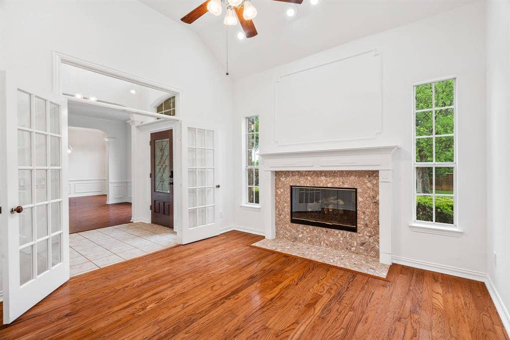 3307 Meadow Wood Drive, Richardson, TX 75082 Vaulted ceiling with a ceiling fan, fireplace with a tile surround and hearth, wood-finish flooring, and French doors