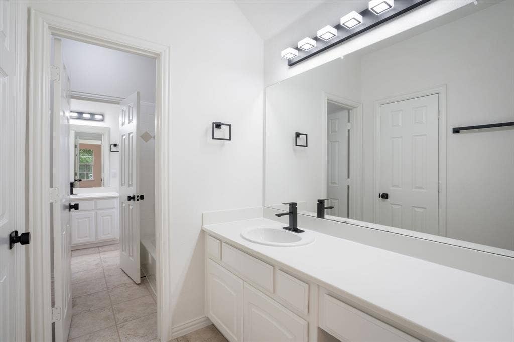 3307 Meadow Wood Drive, Richardson, TX 75082 Dual vanities with white cabinetry and countertops, integrated rectangular sinks, and matte black single-handle faucets