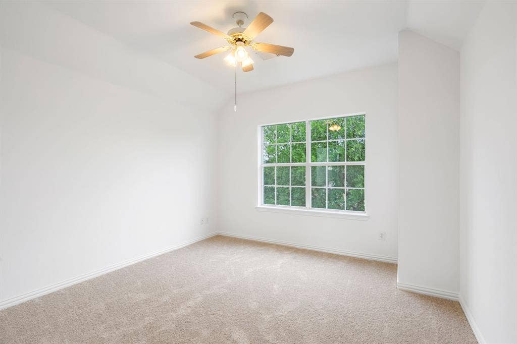 3307 Meadow Wood Drive, Richardson, TX 75082 Vaulted ceiling with an attached ceiling fan and light fixture, large window, and light-toned carpeting