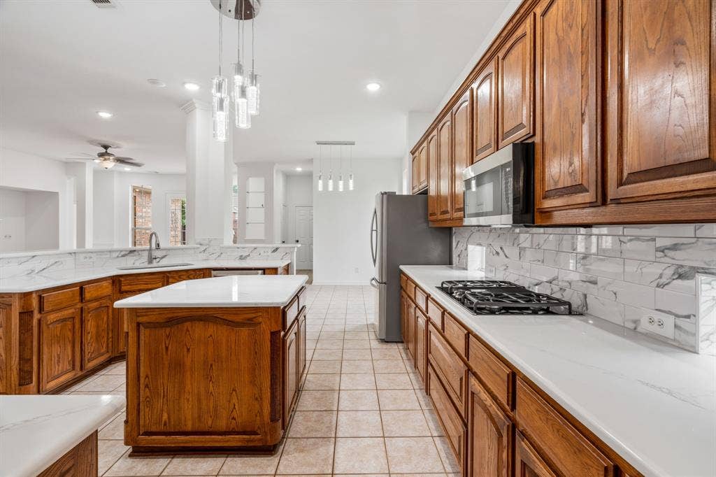 3307 Meadow Wood Drive, Richardson, TX 75082 Spacious kitchen featuring an island, gas cooktop, built-in microwave, wood cabinetry, and tile flooring