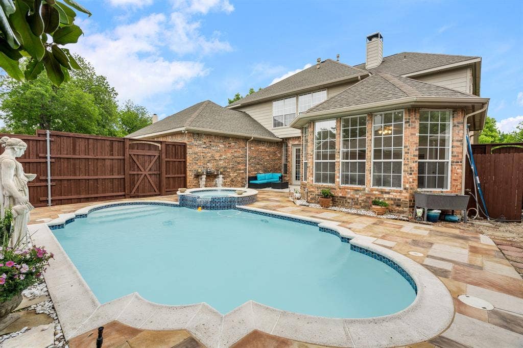 3307 Meadow Wood Drive, Richardson, TX 75082 Brick exterior with multiple windows, an in-ground swimming pool, and an integrated spa