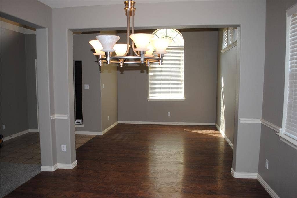 5108 Blackwood Drive, McKinney, TX 75071 Wood-finish flooring, arched window with horizontal blinds, decorative ceiling light fixture, neutral wall color, and white trim