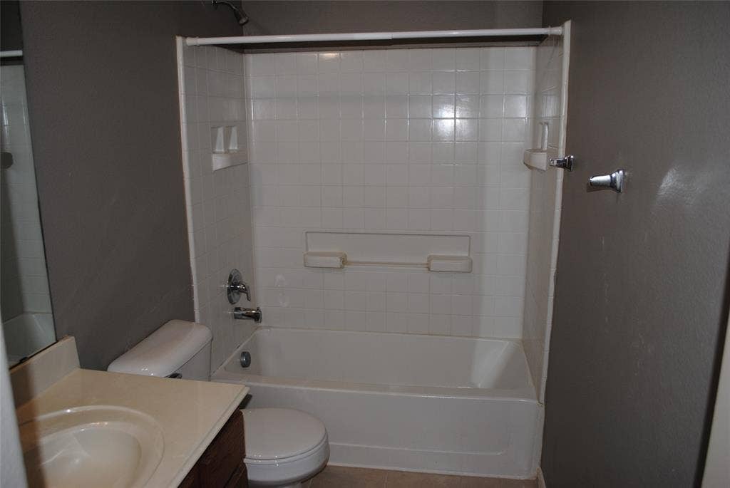 5108 Blackwood Drive, McKinney, TX 75071 Upstairs full bath. White bathtub and shower surround with integrated shelving