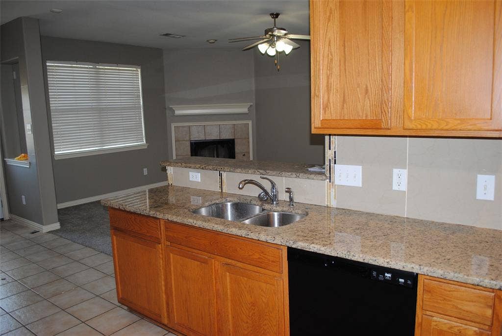 5108 Blackwood Drive, McKinney, TX 75071 Granite countertops, double basin sink, wood cabinetry, black dishwasher, and tile flooring