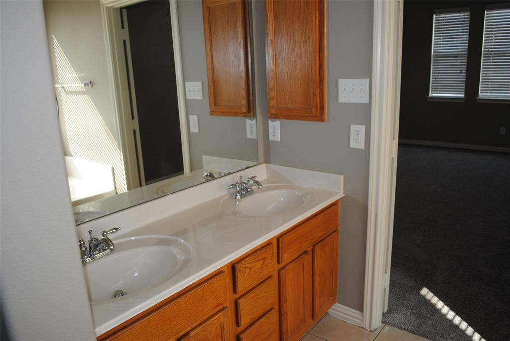 5108 Blackwood Drive, McKinney, TX 75071 Mater bath. Double vanity with integrated sinks, wood cabinetry, and chrome fixtures