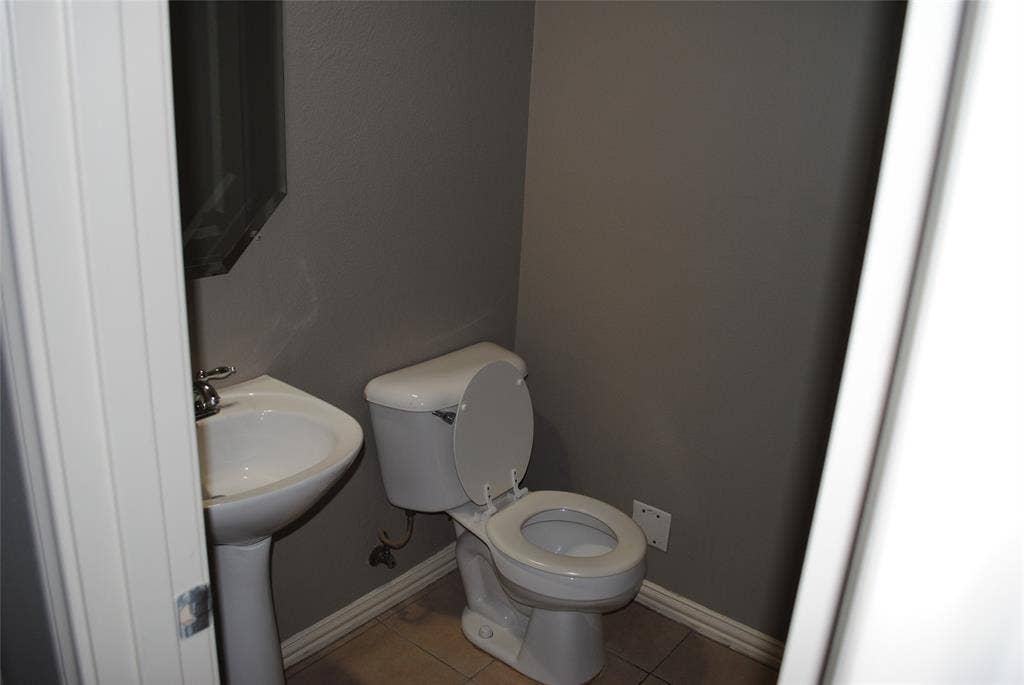 5108 Blackwood Drive, McKinney, TX 75071 Downstairs half bath. Pedestal sink with chrome fixtures, white toilet, and tile flooring