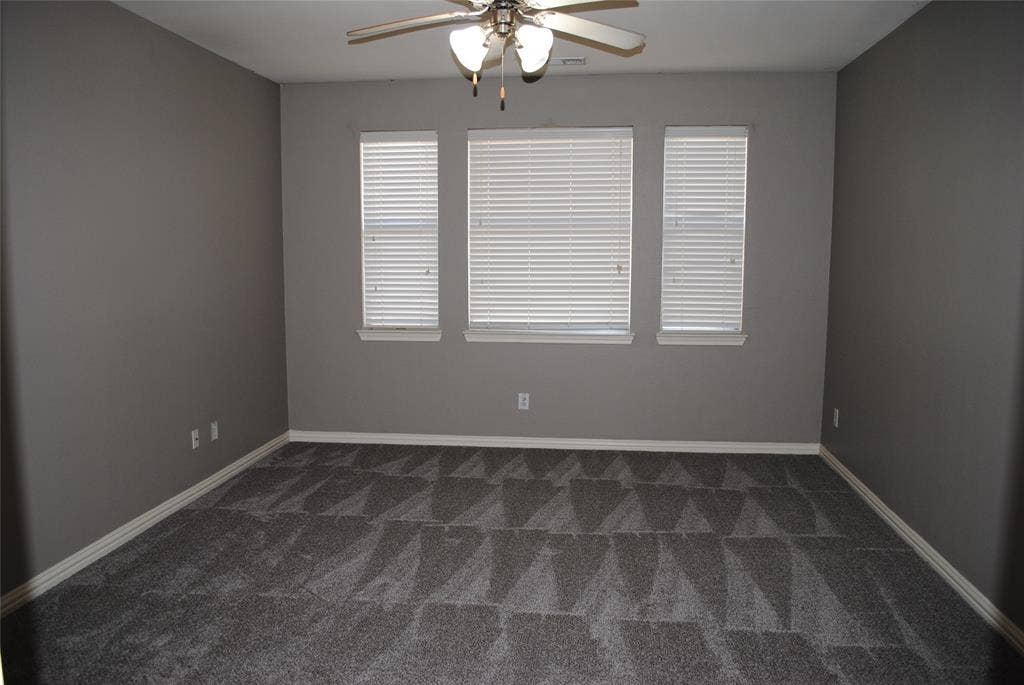 5108 Blackwood Drive, McKinney, TX 75071 Spacious room featuring neutral painted walls, three windows with blinds, and a ceiling fan with integrated lighting