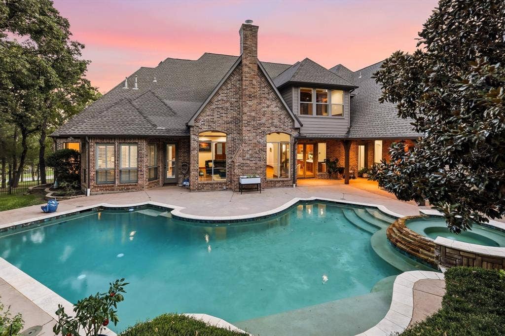 Brick exterior, multi-level shingle roof, expansive swimming pool, integrated spa, and covered patio