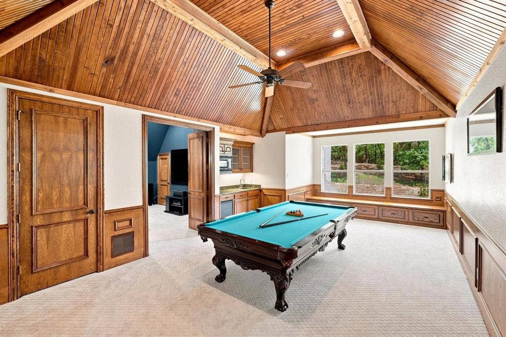 Vaulted wood-paneled ceiling, integrated wet bar with cabinetry, built-in window seating with storage, and a series of three windows