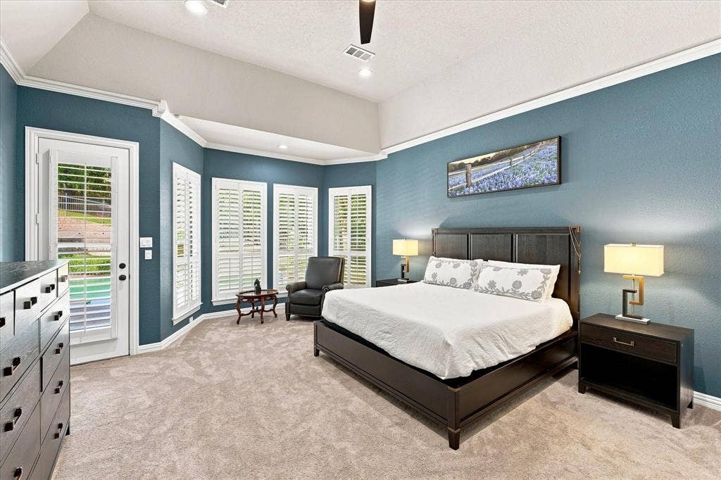 Vaulted ceiling with crown molding, recessed lighting, bay window with plantation shutters, and direct outdoor access