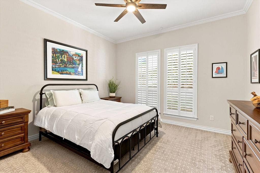 Textured carpeting, crown molding, plantation shutters, and a ceiling fan with integrated lighting