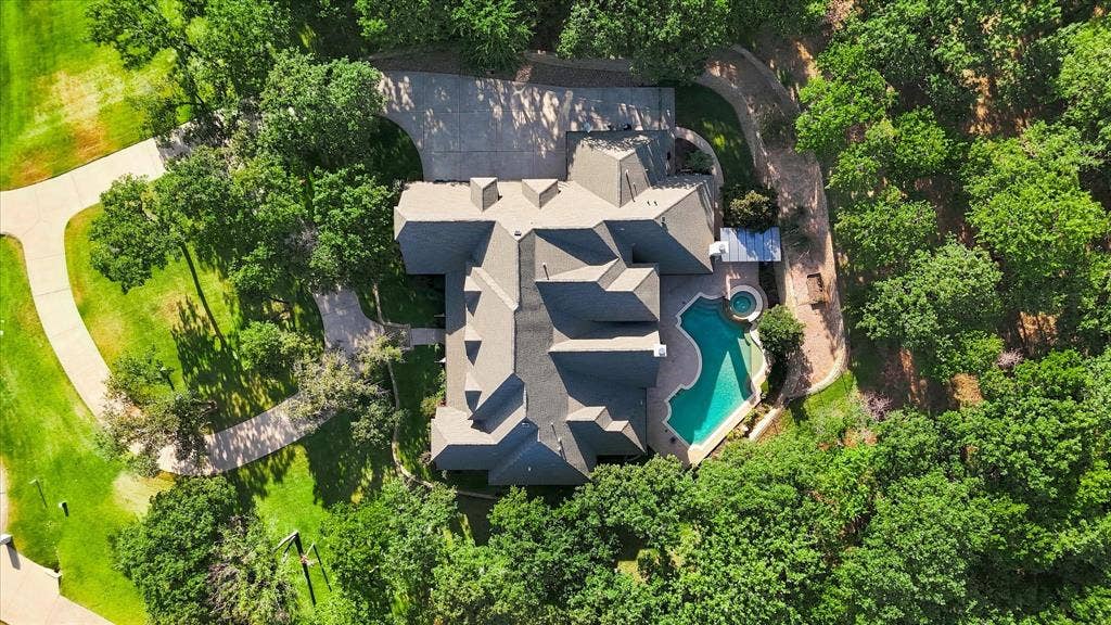 Expansive property featuring a multi-level roofline, large swimming pool, integrated spa, and extensive surrounding foliage