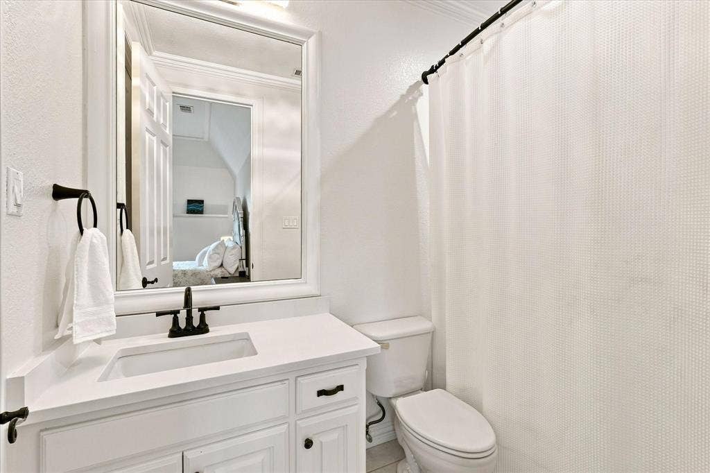 White vanity with integrated sink, matte black faucet, and framed mirror