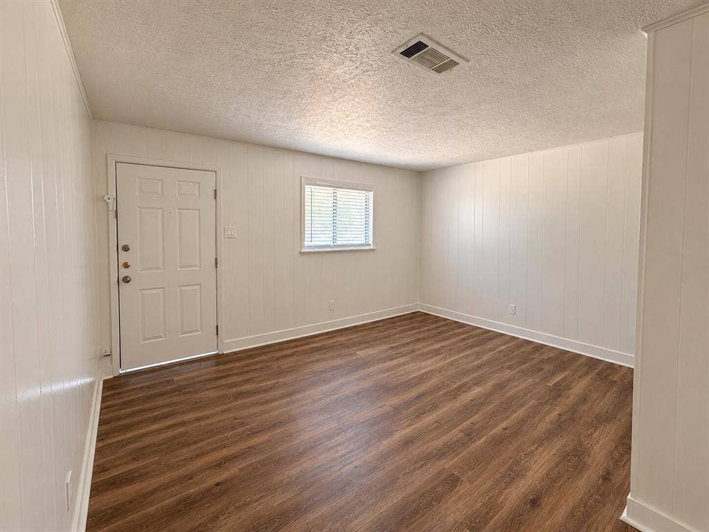 2002 Washington Street, #3, Commerce, TX 75428 Wood-finish flooring with white baseboards, vertical paneling, and a panel door with multiple lites