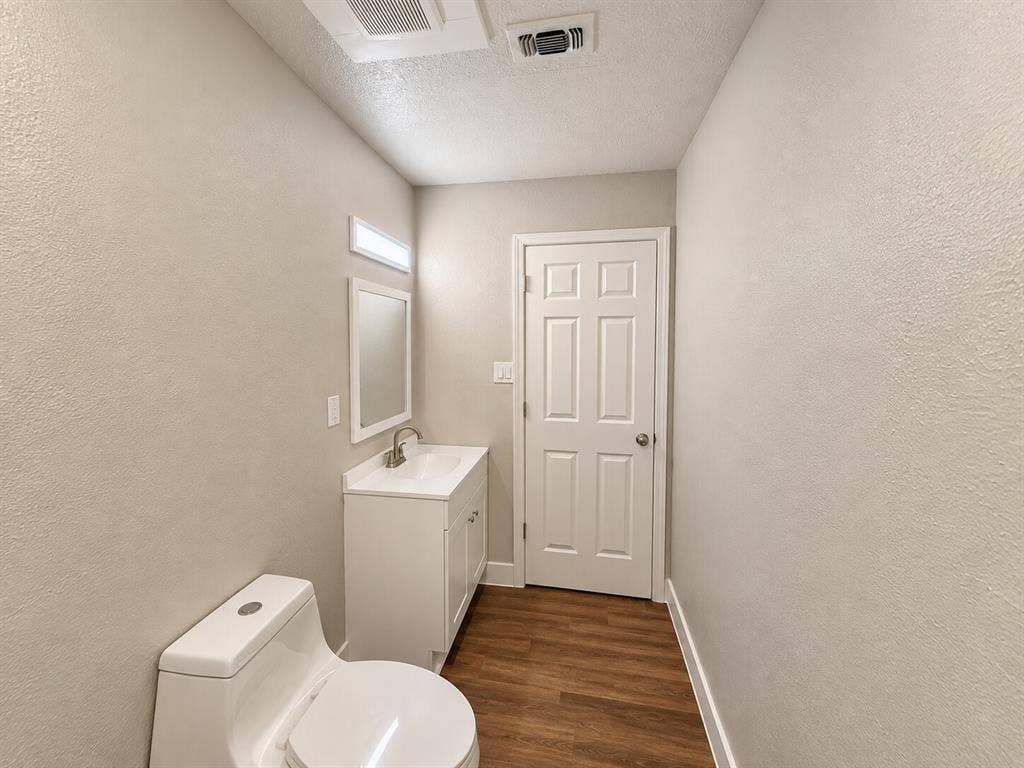 2002 Washington Street, #3, Commerce, TX 75428 White vanity with an integrated sink, framed mirror, and wood-finish flooring