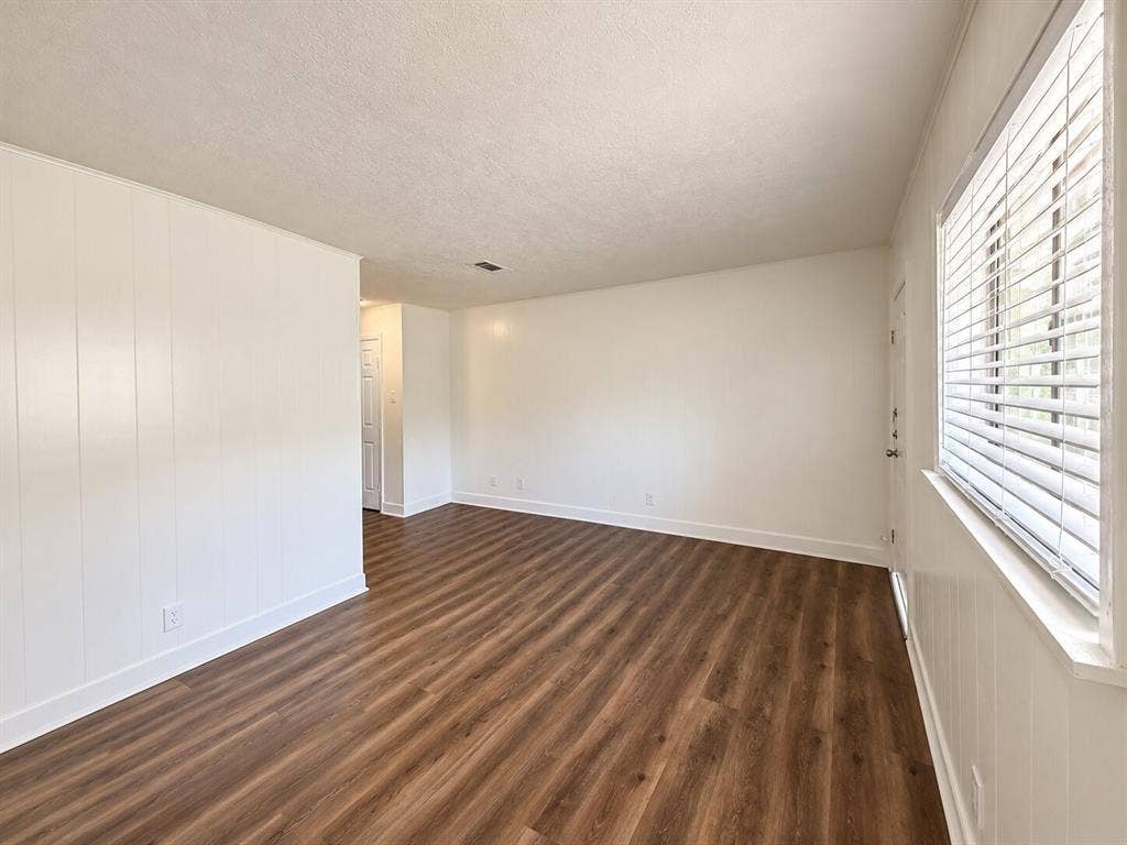 2002 Washington Street, #3, Commerce, TX 75428 Wood-finish flooring, white paneled accent wall, white window blinds, and white trim throughout