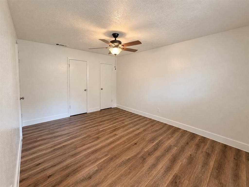 2002 Washington Street, #3, Commerce, TX 75428 Wood-finish flooring, ceiling fan with integrated lighting, two white panel doors, and neutral wall tones