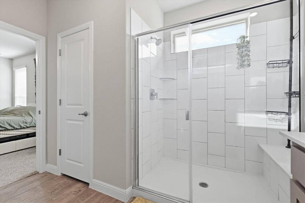 Walk-in shower with clear glass enclosure, white subway tile surround, integrated shower bench, and a transom window
