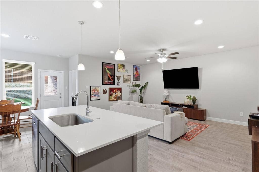 Kitchen island with an undermount sink, quartz countertop, and pendant lighting