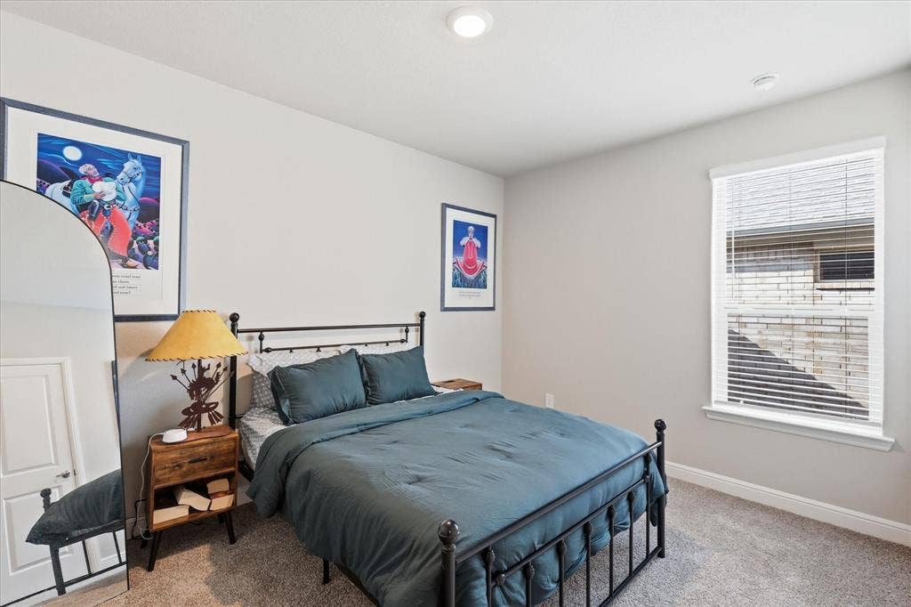 Recessed lighting illuminates the space, featuring light-colored walls and a window with blinds