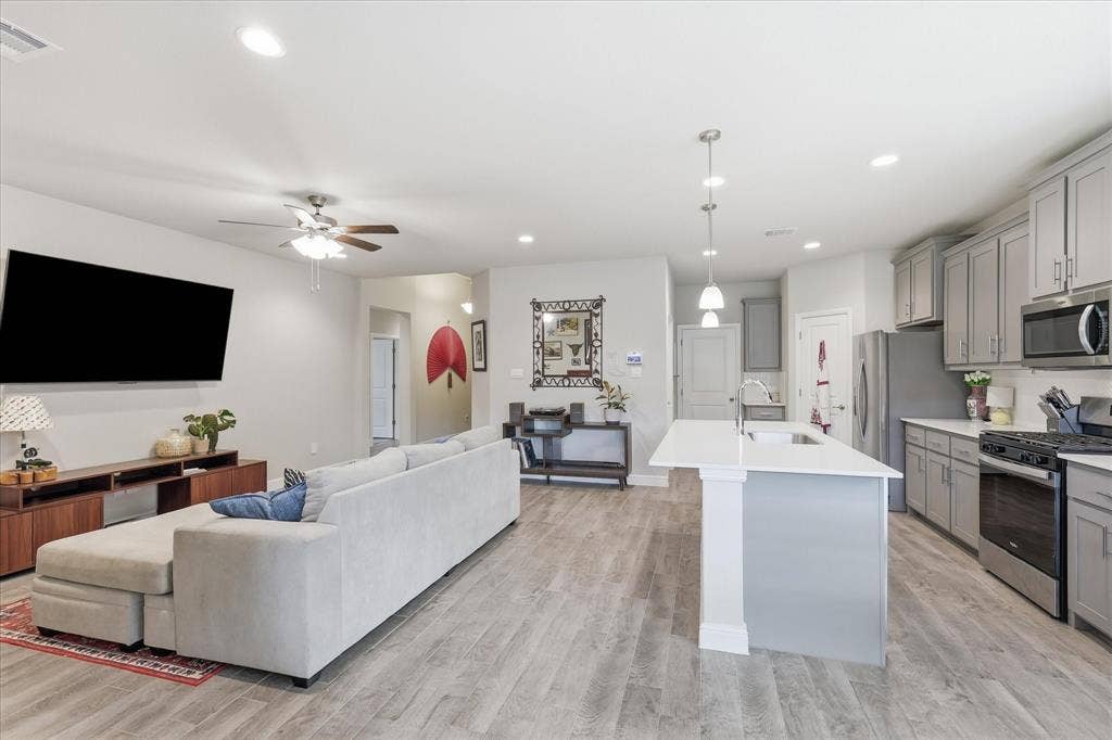 Open-concept living space featuring wood-finish flooring, recessed lighting, and a ceiling fan